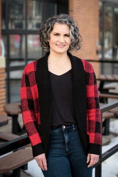 Carla Laureano leaning on a iron railing outside a restaurant