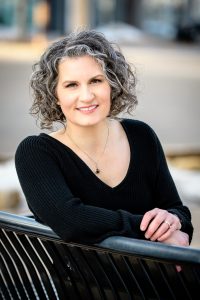 Photo of Carla Laureano smiling sitting on a park bench